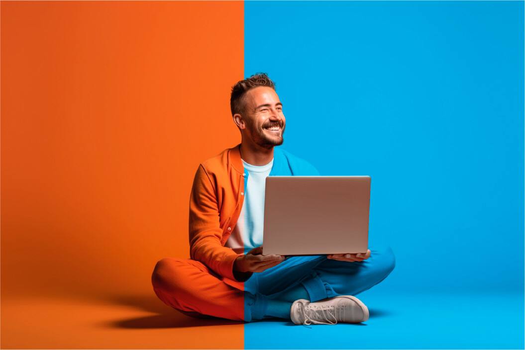Profissional sorridente sentado com um port�til, em fundo laranja e azul